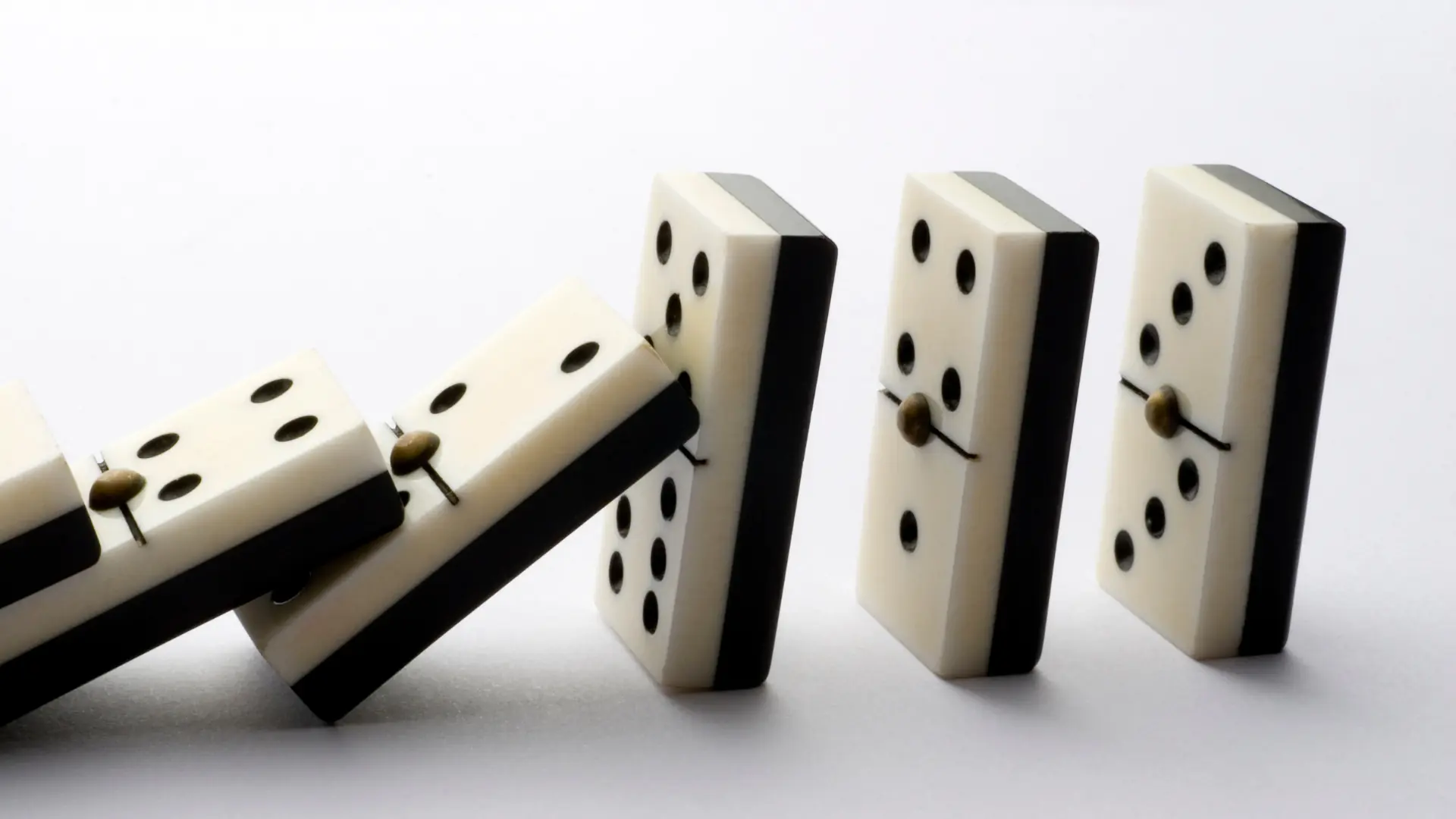 Dominoes falling, symbolizing the cascading impact of poor schema decisions on system stability